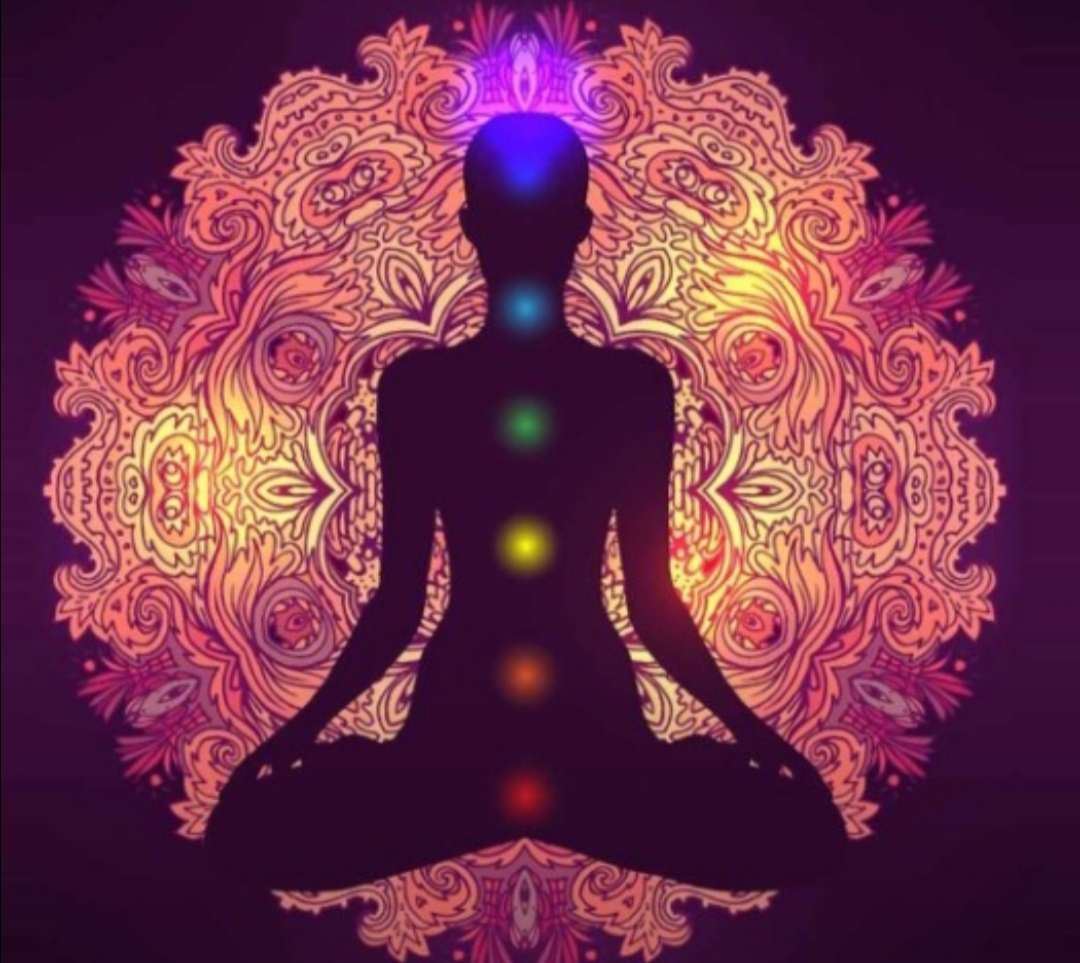 Meditáló alak a hét csakra színeivel, mandala háttérrel